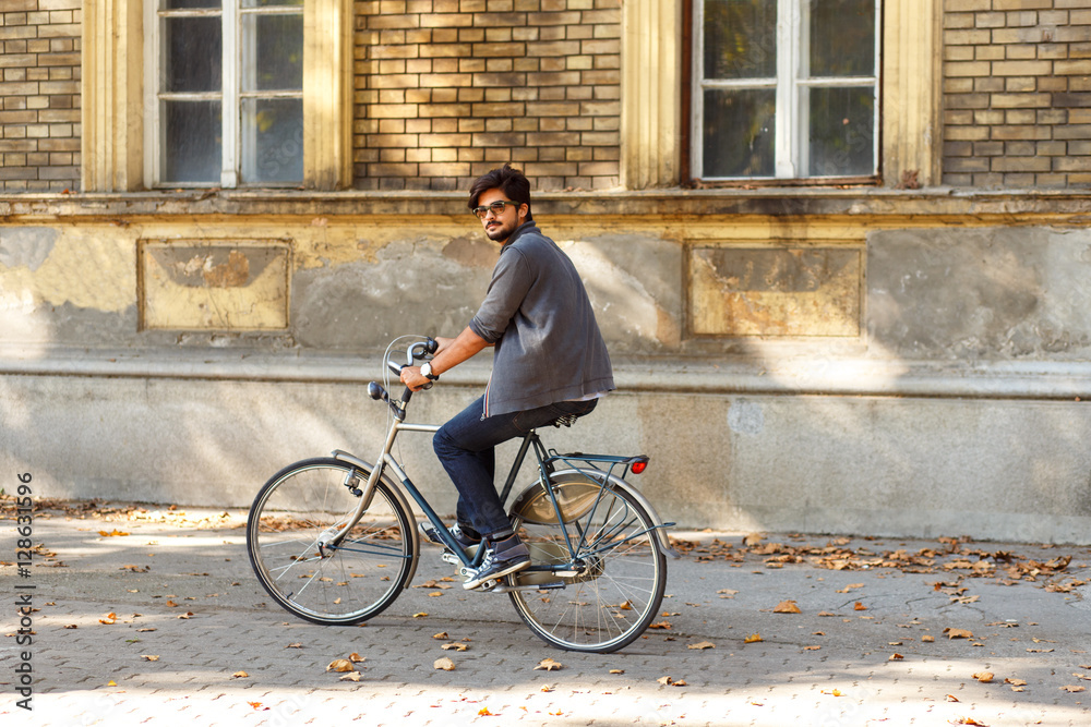 Fototapeta premium Young handsome ride a bicycle on sidewalk in the city.