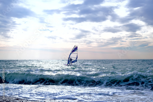 Windsurfer surfing through wavy sea with sail board
