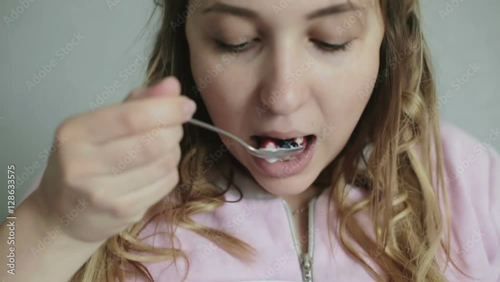 Young girl eating fresh berries with a spoon. Young girl eating fresh berries with a spoon.