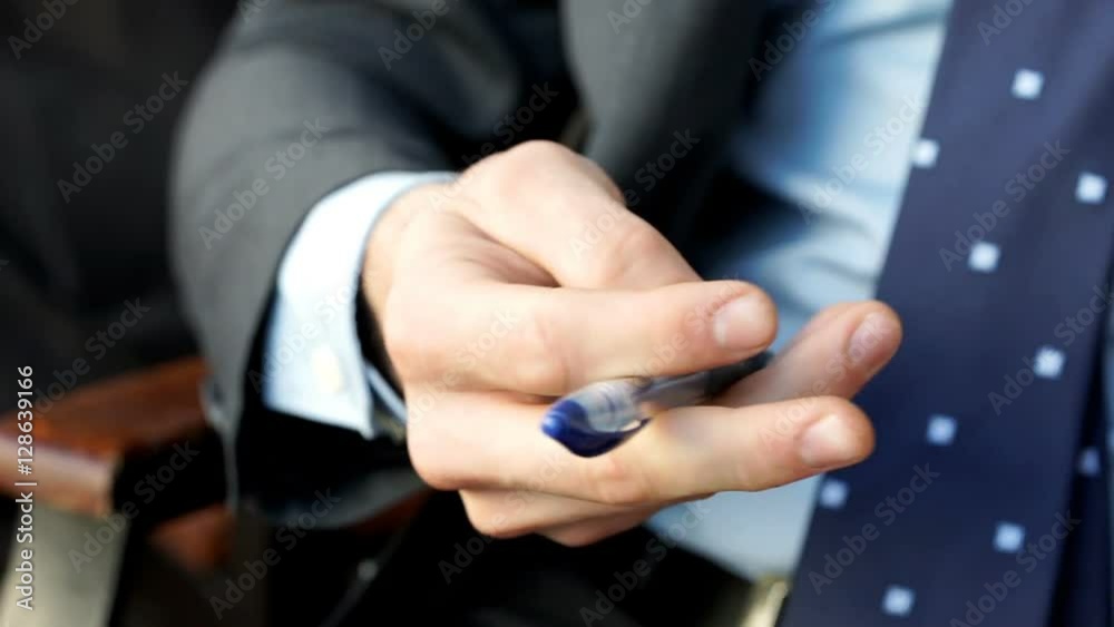 Businessman holding a pen and playing with it, steadycam shot
