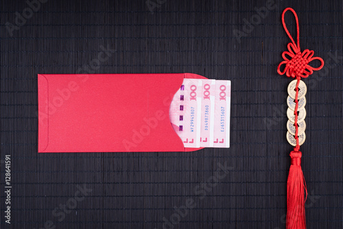 chinese lucky coins and red envelope on black bamboo mat