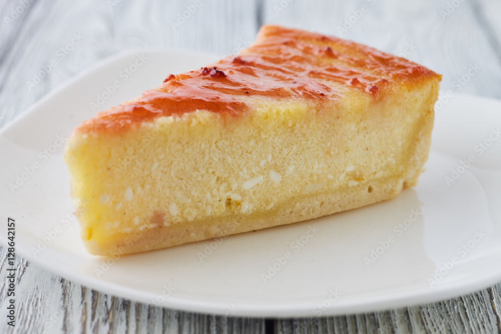 Slice of the New York cheesecake on a white plate on a wooden background Slice of the New York cheesecake on a white plate on a wooden background