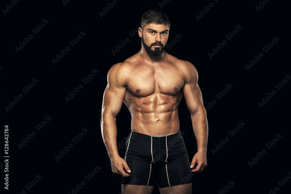 Strong Athletic Man Fitness Model Torso showing six pack abs. isolated on black background with copyspace