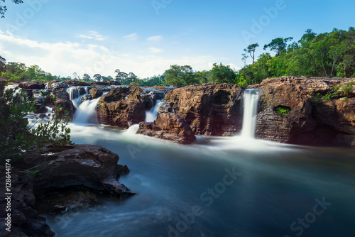 Waterfall in forest with blue sky background in long exposure 