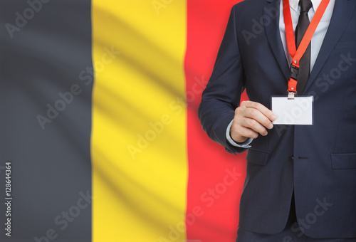 Businessman holding name card badge on a lanyard with a national flag on background - Belgium