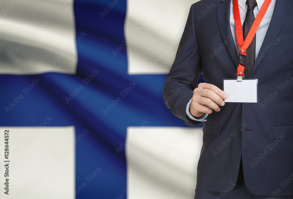 Businessman holding name card badge on a lanyard with a national flag on background - Finland Businessman holding name card badge on a lanyard with a national flag on background - Finland