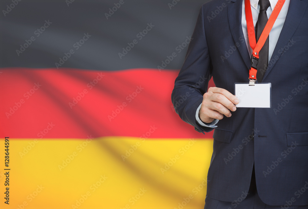 Businessman holding name card badge on a lanyard with a national flag on background - Germany Businessman holding name card badge on a lanyard with a national flag on background - Germany