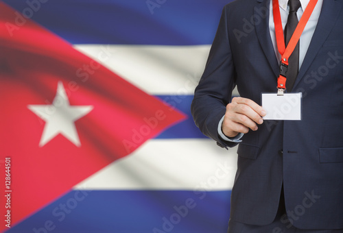 Businessman holding name card badge on a lanyard with a national flag on background - Cuba