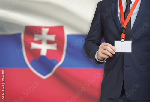 Businessman holding name card badge on a lanyard with a national flag on background - Slovakia