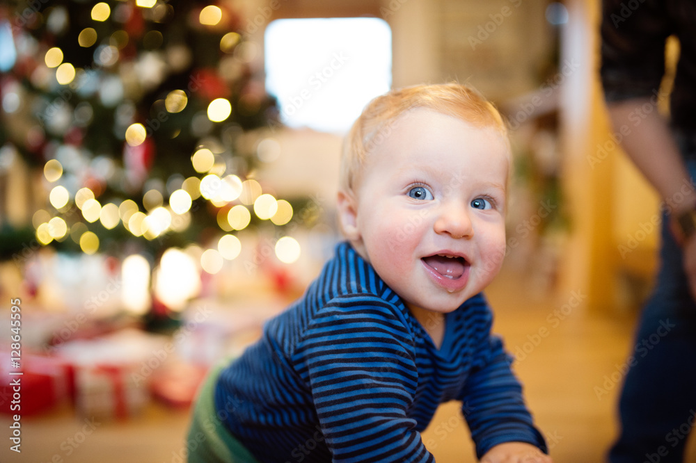 Fototapeta premium Little boy at home against Christmas tree and presents