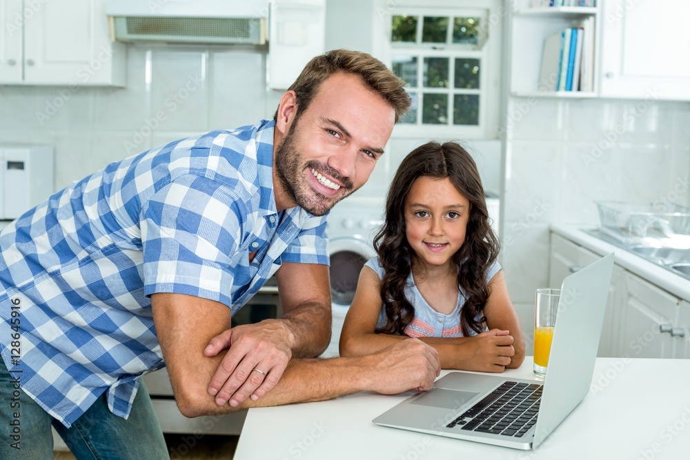 Happy father and daughter with laptop in kitchen
