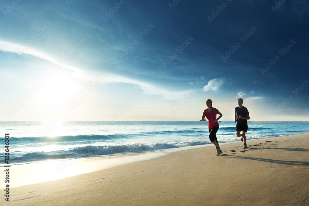 Man and women running on tropical beach at sunset Man and women running on tropical beach at sunset