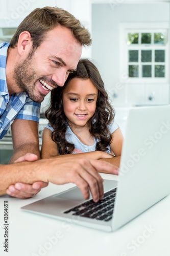 Man with daughter using laptop computer at home