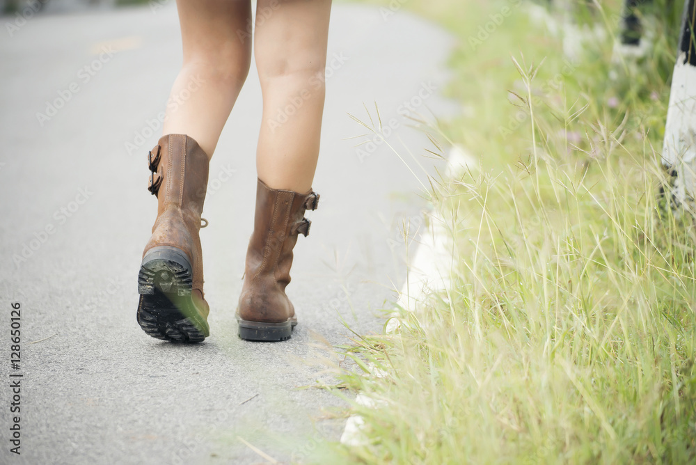 Closeup picture of a beautiful woman's legs,wearing brown boots walking alone on the road. Closeup picture of a beautiful woman's legs,wearing brown boots walking alone on the road.