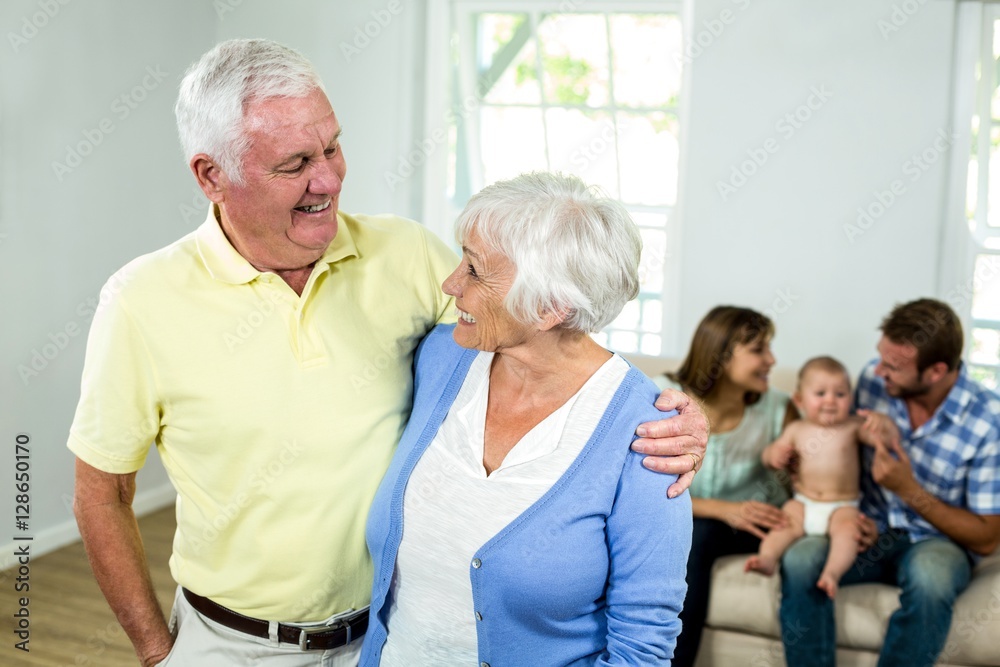 Senior couple with family sitting on sofa in background Senior couple with family sitting on sofa in background
