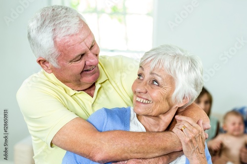 Happy couple embracing while family in background