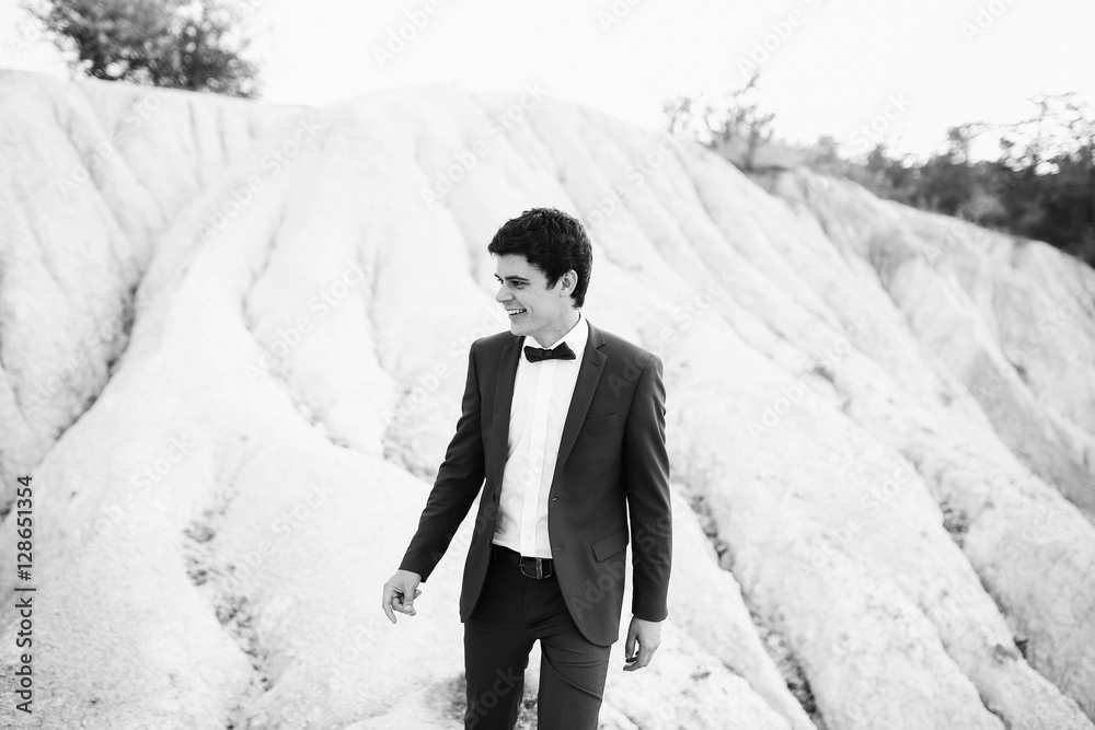 handsome and young groom in a suit walking outdoors handsome and young groom in a suit walking outdoors