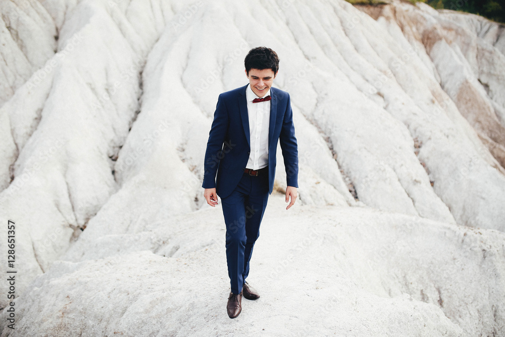 handsome and young groom in a suit walking outdoors