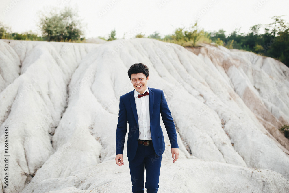 handsome and young groom in a suit walking outdoors handsome and young groom in a suit walking outdoors