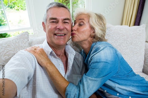 Excited senior woman kissing husband while sitting on sofa © WavebreakmediaMicro