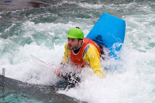 Teenager in a kayak bobbing vertically in fast flowing water