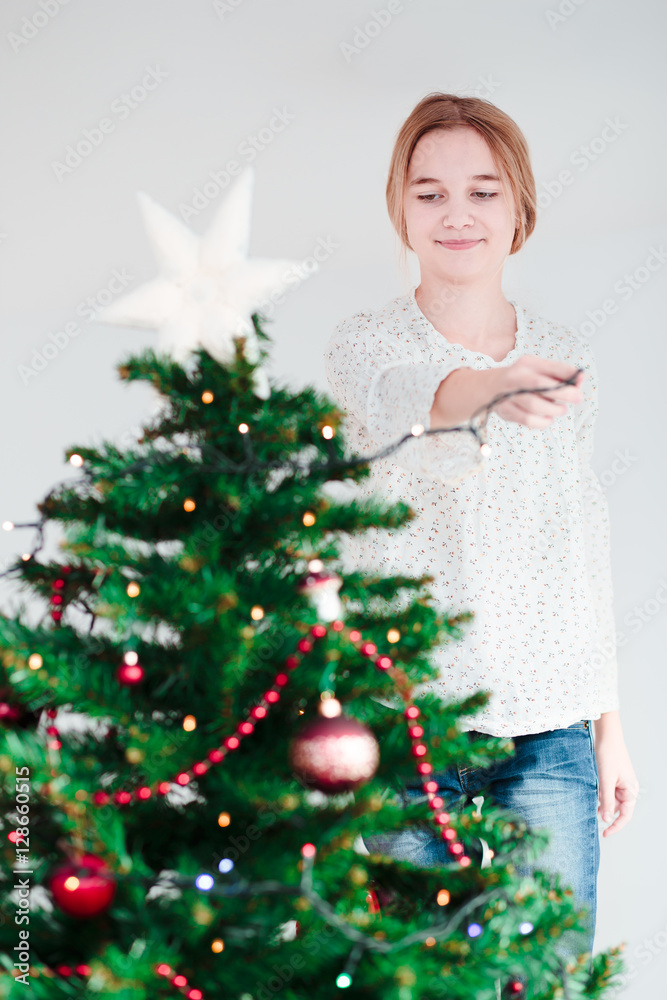 Young girl decorating Christmas tree with lights Young girl decorating Christmas tree with lights