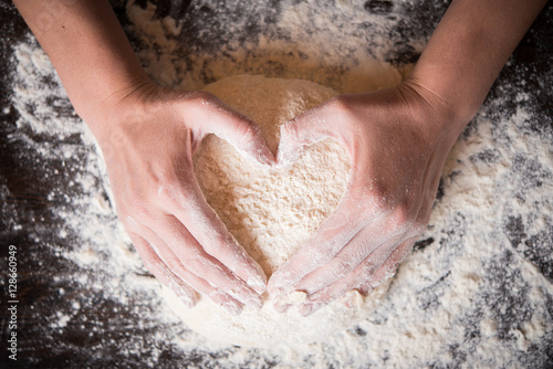 Female hands holding dough in heart shape