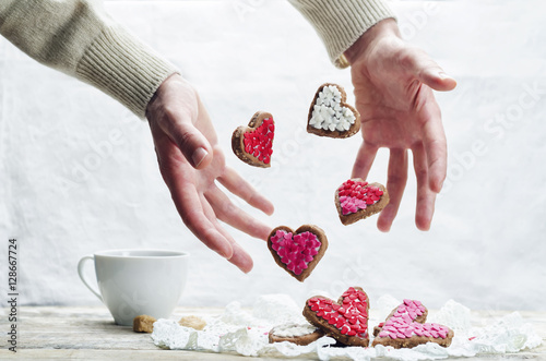 Male hand with flying cookies in the forms of hearts