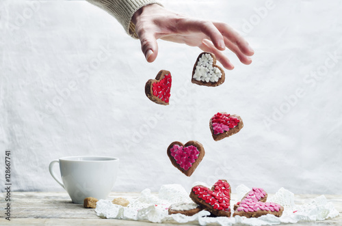 Male hand with flying cookies in the forms of hearts