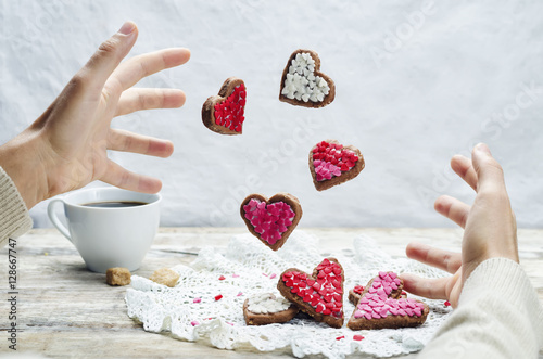 Male hand with flying cookies in the forms of hearts