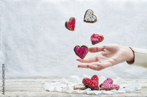 Male hand with flying cookies in the forms of hearts