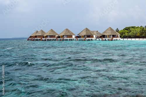 Typically Maldivian Landscape with turquoise ocean, blue sky, white sand beach and beach villas