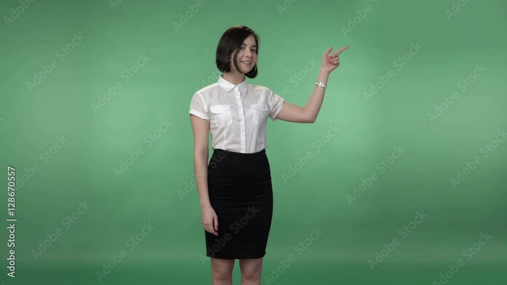 Young asian woman in a white shirt and black skirt pointing to something by the hand and smiling, chroma key green screen background Young asian woman in a white shirt and black skirt pointing to something by the hand and smiling, chroma key green screen background
