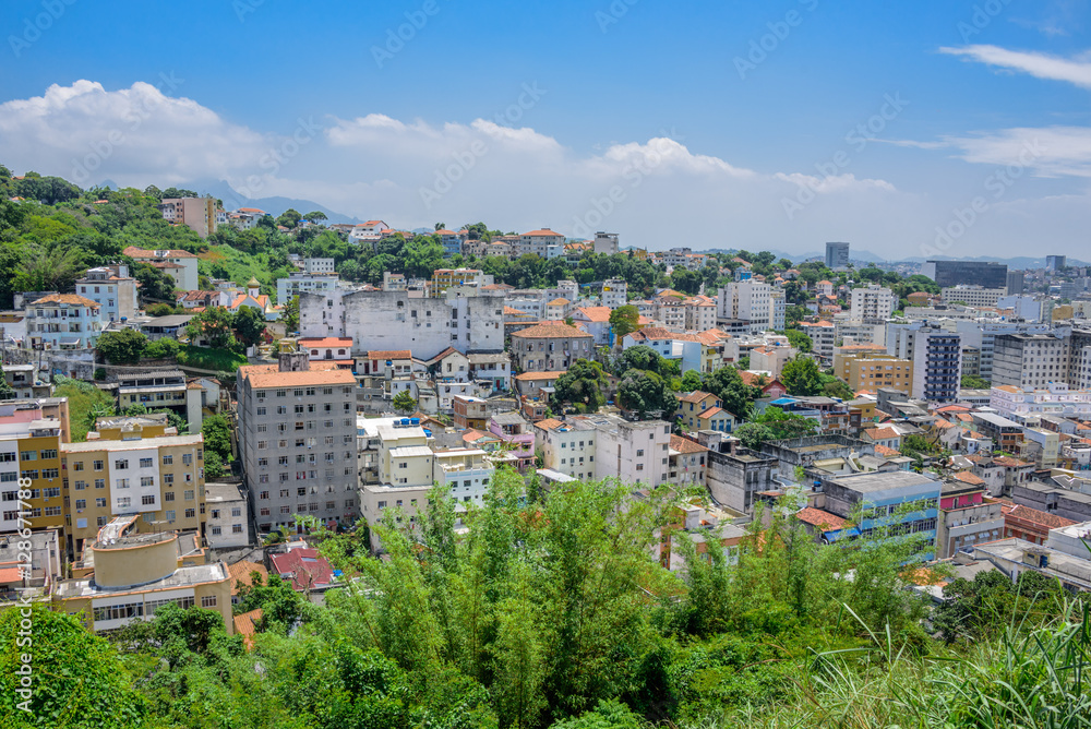 View of typical residential houses in the green area of Santa Teresa, blue sky and white clouds at hot, sunny day in Rio de Janeiro, Brazil