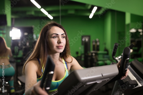 Sport woman riding an exercise bike in gym