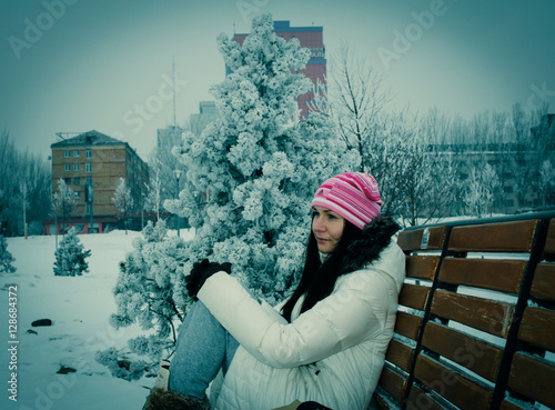 Girl thoughtfully looking into the distance, sitting on a bench