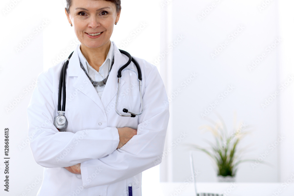 Happy female doctor standing in hospital. Medicine and health care concept. Happy female doctor standing in hospital. Medicine and health care concept.