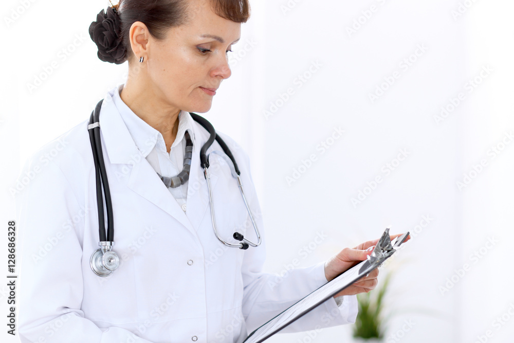 Happy female doctor standing in hospital. Medicine and health care concept. Happy female doctor standing in hospital. Medicine and health care concept.