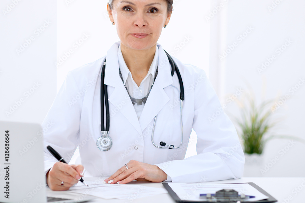Female doctor at the table and filling up medical form. Medicine and health care concept. Female doctor at the table and filling up medical form. Medicine and health care concept.