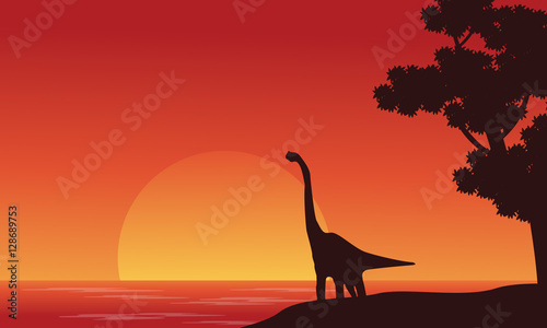 Silhouette of dinosaur brachiosaurus on riverbank