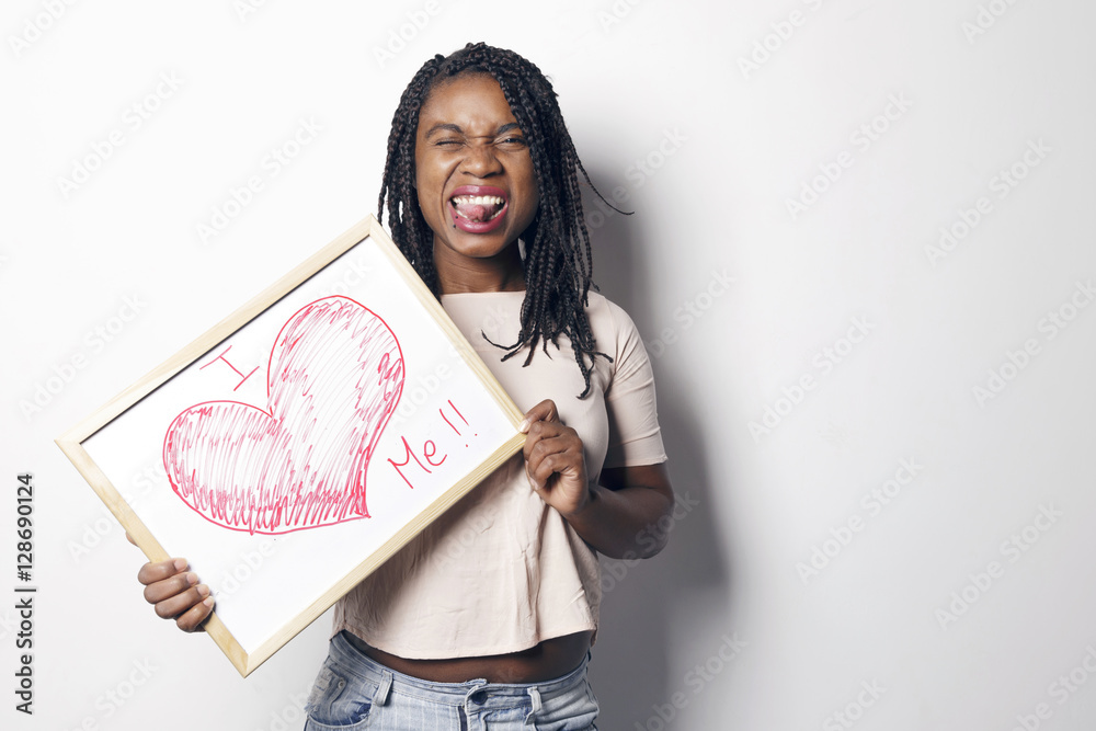 Φωτογραφία Happy young african woman holding an white board, with the I love me message written on it, over a white background