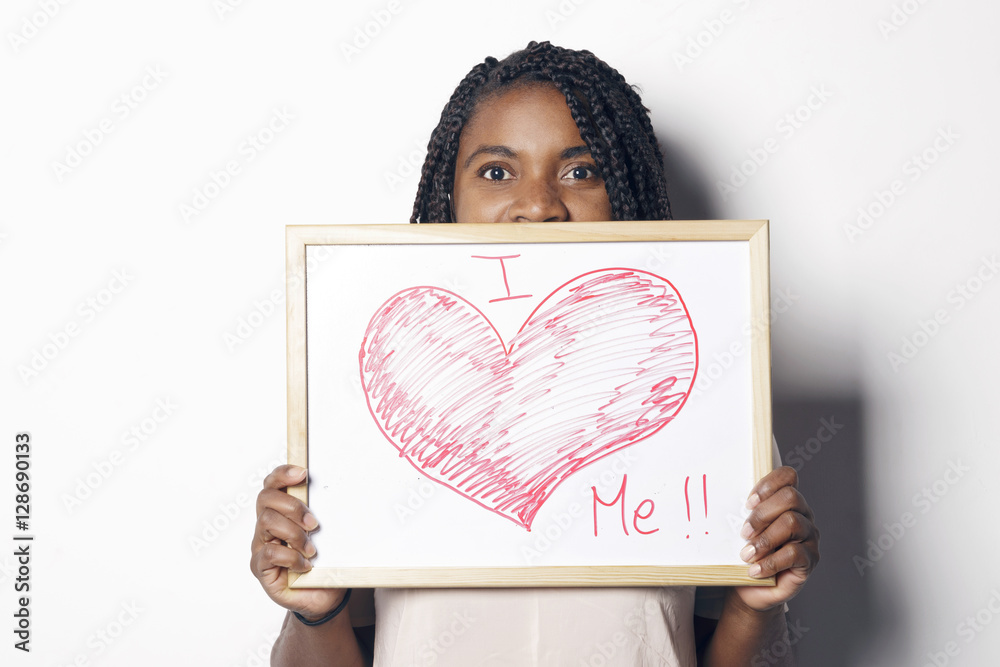 Φωτογραφία Happy young african woman holding an white board, with the I love me message written on it, over a white background