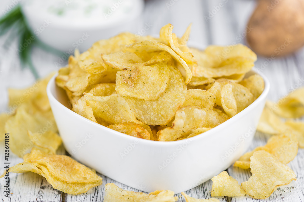 Portion of Potato Chips with Sour Cream taste on wooden backgrou Portion of Potato Chips with Sour Cream taste on wooden backgrou