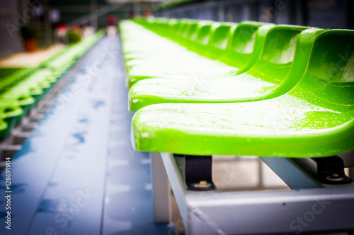 Close up chair green,.green plastic stadium seats arranged in a row. The image has been made before the beginning of a tennis game,.Blurred background of crowd of people at the stadium