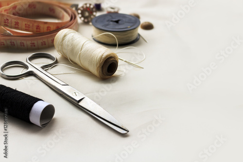 sewing tools on white fabric background. over light, retro tone and high contrast. [blur and select focus background]