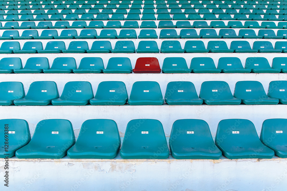 Obraz premium Single red seat or bench in the middle or center of green chair in the stadium.