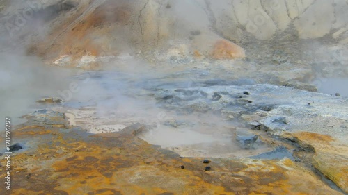 boiling mud pots of geothermal area Krysuvik in Iceland, ground is colored in bright colors photo