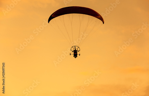 Silhouette of para moter flies on background of sunset sky