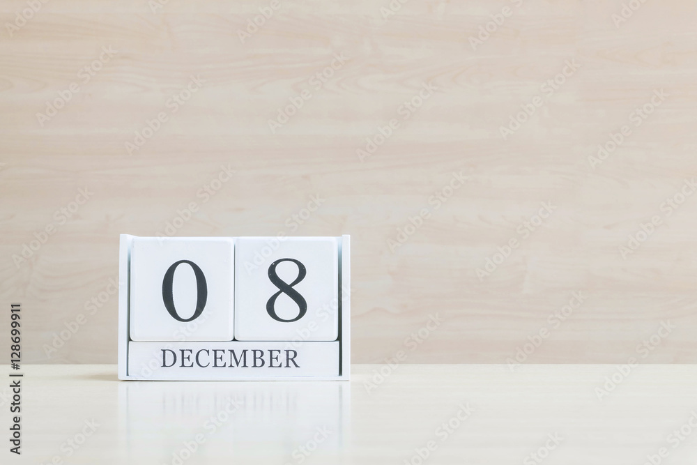 Closeup surface white wooden calendar with black 8 december word on blurred brown wood desk and wood wall textured background with copy space , selective focus at the calendar Closeup surface white wooden calendar with black 8 december word on blurred brown wood desk and wood wall textured background with copy space , selective focus at the calendar