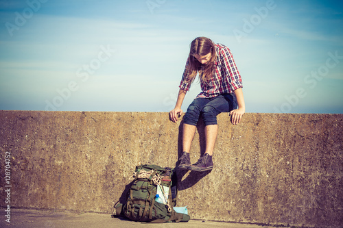 Man tourist backpacker sitting on grunge wall outdoor